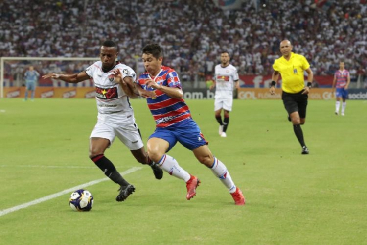 Osvaldo, ex-Fortaleza, tenta drible contra marcador do Vitória. 