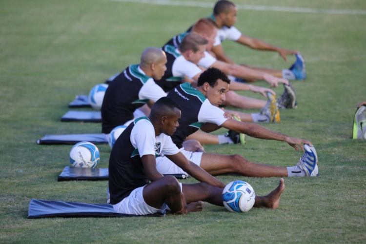 Dois jogadores de futebol fazendo exercícios de alongamento no campo.  treinamento de futebol em estádio ao ar livre, treino em equipe antes do  jogo