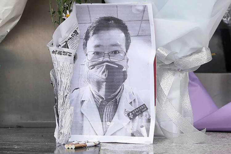 A photo of the late ophthalmologist Li Wenliang is seen with flower bouquets at the Houhu Branch of Wuhan Central Hospital in Wuhan in China's central Hubei province on February 7, 2020. - A Chinese doctor who was punished after raising the alarm about China's new coronavirus died from the pathogen on February 7, sparking an outpouring of grief and anger over a worsening crisis that has now killed more than 630 people. (Photo by STR / AFP) / China OUT