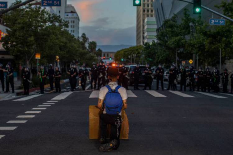 Um manifestante se ajoelha em frente à força policial, em ato de protesto em Los Angeles 