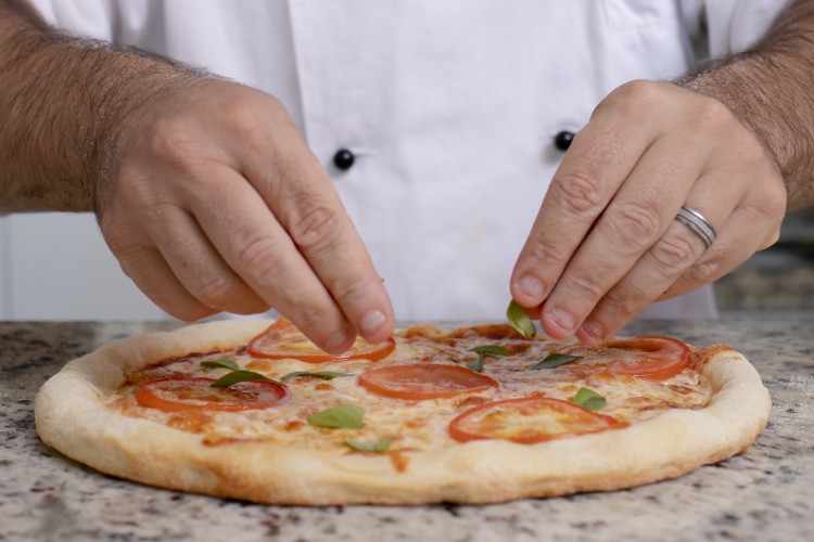 Valerio Dionisi, consultor de pizzarias, finaliza a pizza após ter ido para o forno  (Foto:/ Aurelio Alves/ O POVO).