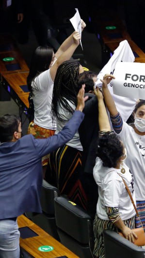 Opositores do governo do presidente Jair Bolsonaro se manifestam com cartazes e camisetas com os dizeres â.GenocÃ­dio foraâ.. durante discurso na sessÃ£o do Congresso Nacional em BrasÃ­lia, em 3 de fevereiro de 2021. - O Congresso brasileiro elegeu na segunda-feira dois aliados do presidente Jair Bolsonaro Ã  frente do Senado e da CÃ¢mara, uma importante vitÃ³ria do lÃ­der da extrema direita em sua busca por revigorar seus esforÃ§os de reeleiÃ§Ã£o para 2022. (Foto Sergio Lima / AFP)