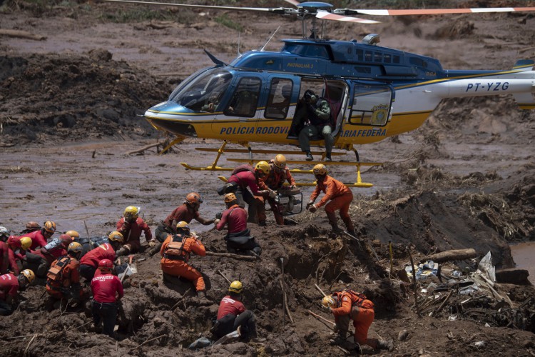 Nesta foto de arquivo tirada em 28 de janeiro de 2019, os bombeiros recebem equipamento para abrir um veículo encontrado na lama enquanto buscam as vítimas do rompimento da barragem em uma mina de minério de ferro pertencente à gigante mineradora brasileira Vale, perto da cidade de Brumadinho, estado de Minas Gerais, sudeste do Brasil.