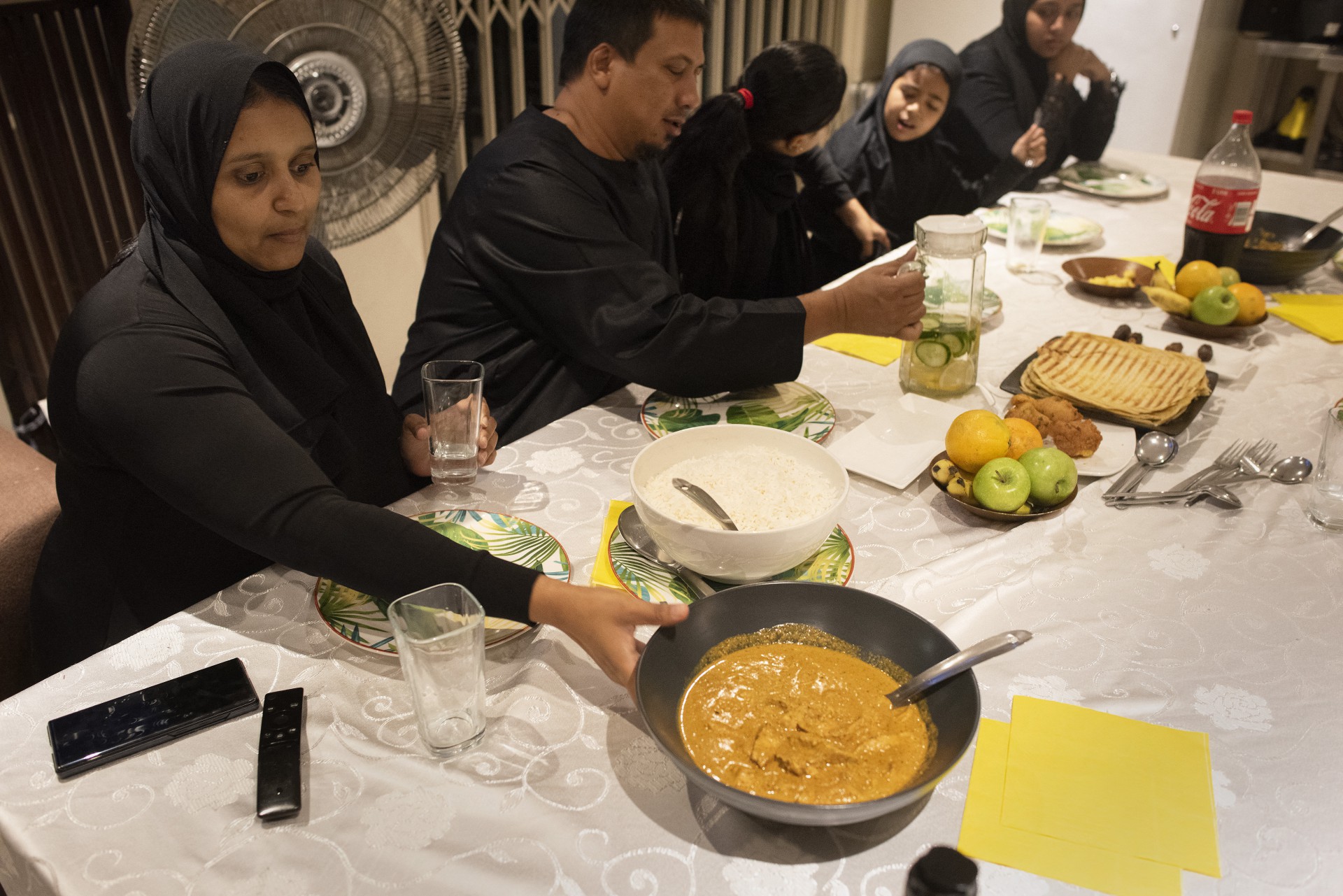 Washima Martin(L) brings Butter Chicken to the table for her family in Newfields during Iftar, the evening meal that will end the daily fast at sunset, on the first day of the Islamic holy month of Ramadan, in Cape Town, on April 14, 2021. (Photo by RODGER BOSCH / AFP)
      Caption (Foto: AFP)