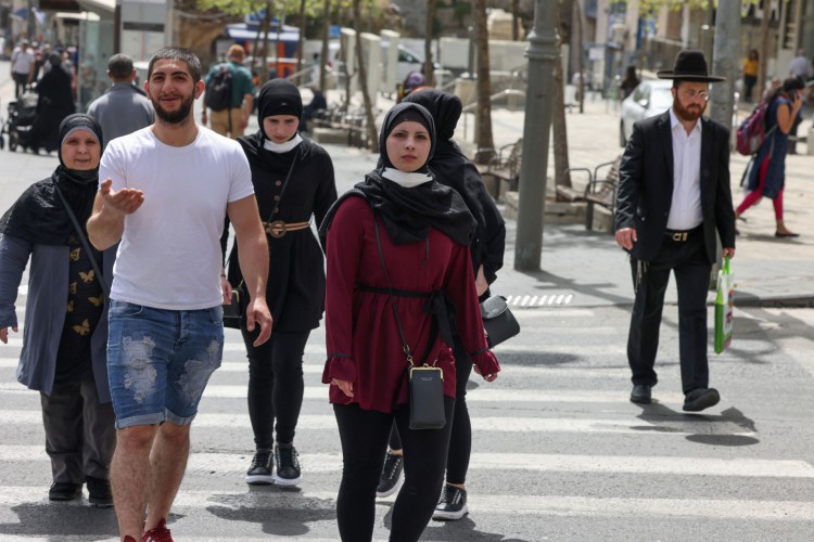 Pessoas caminham em uma rua em Jerusalém, em 18 de abril de 2021, depois que as autoridades israelenses anunciaram que as máscaras faciais para prevenção COVID-19 não eram mais necessárias ao ar livre