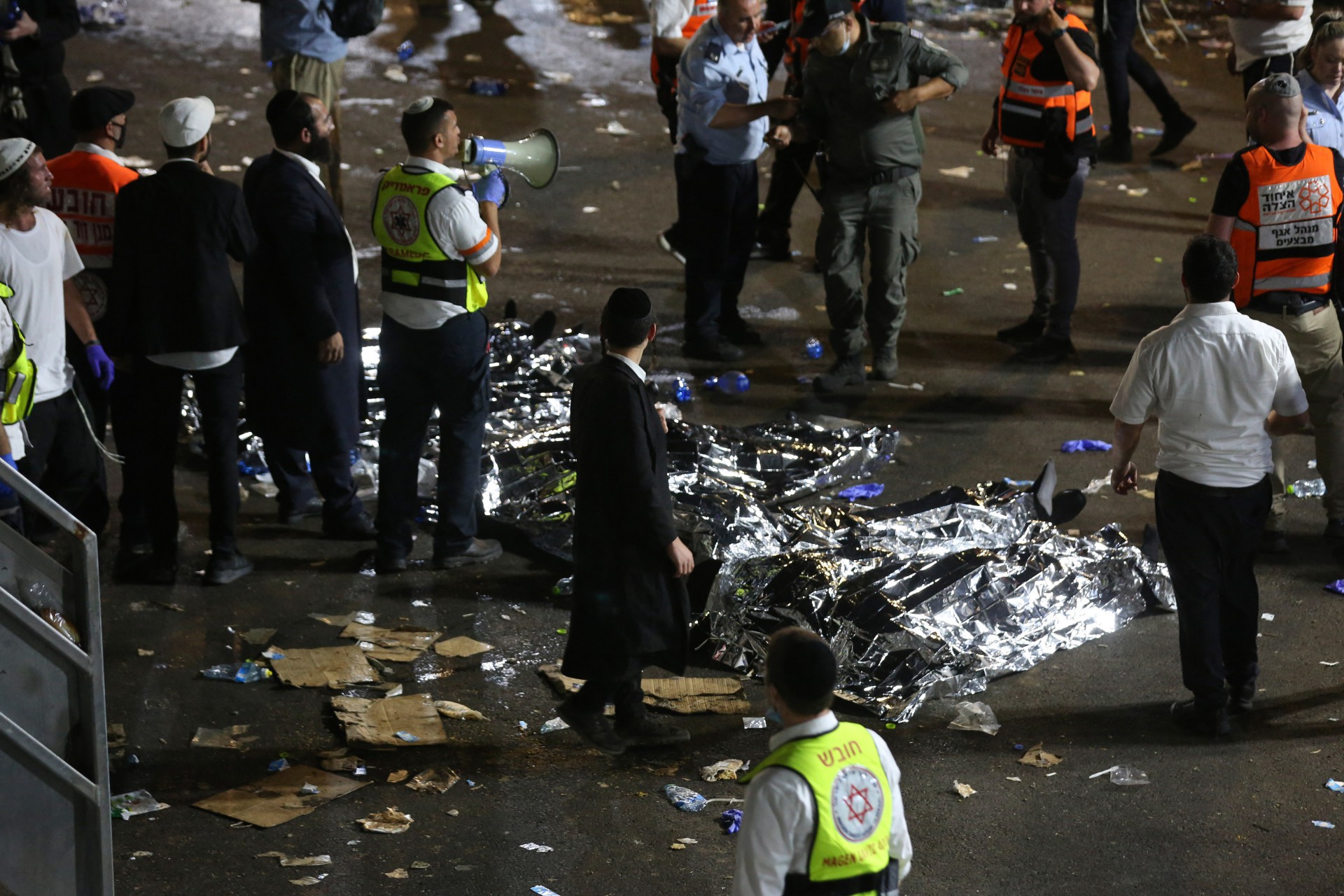 Homens judeus ultra-ortodoxos ficam ao lado de corpos cobertos depois que dezenas de pessoas foram mortas e outros feridos depois que uma arquibancada desabou em Meron, Israel, onde dezenas de milhares de pessoas se reuniram para celebrar o festival de Lag Ba'omer no local no norte Israel no início de 30 de abril de 2021. - Dezenas de pessoas foram mortas em uma corrida em um local de peregrinação judaica no norte de Israel no início de 30 de abril, informaram os serviços de resgate. Dezenas de milhares de judeus estavam participando da peregrinação anual na quinta-feira, para a festa de Lag BaOmer. Mas depois da meia-noite, uma arquibancada desabou, provocando cenas de pânico. (Foto de David COHEN / JINI PIX / AFP) / Israel OUT (Foto: David COHEN / JINI PIX / AFP)