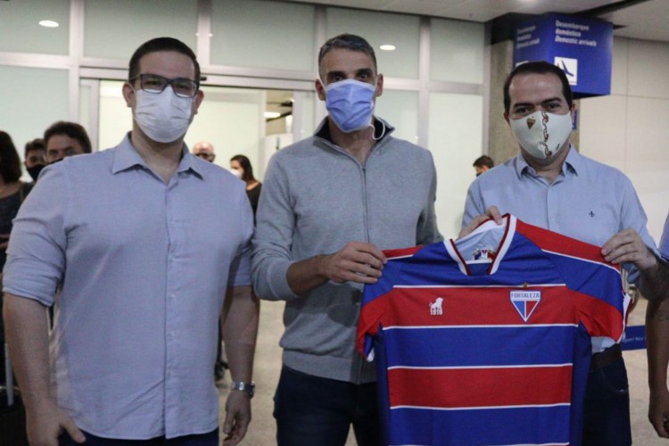 Técnico do Fortaleza, Juan Pablo Vojvoda segurando a camisa do clube, ao lado do presidente Marcelo Paz e do Diretor de Futebol Alex Santiago. 