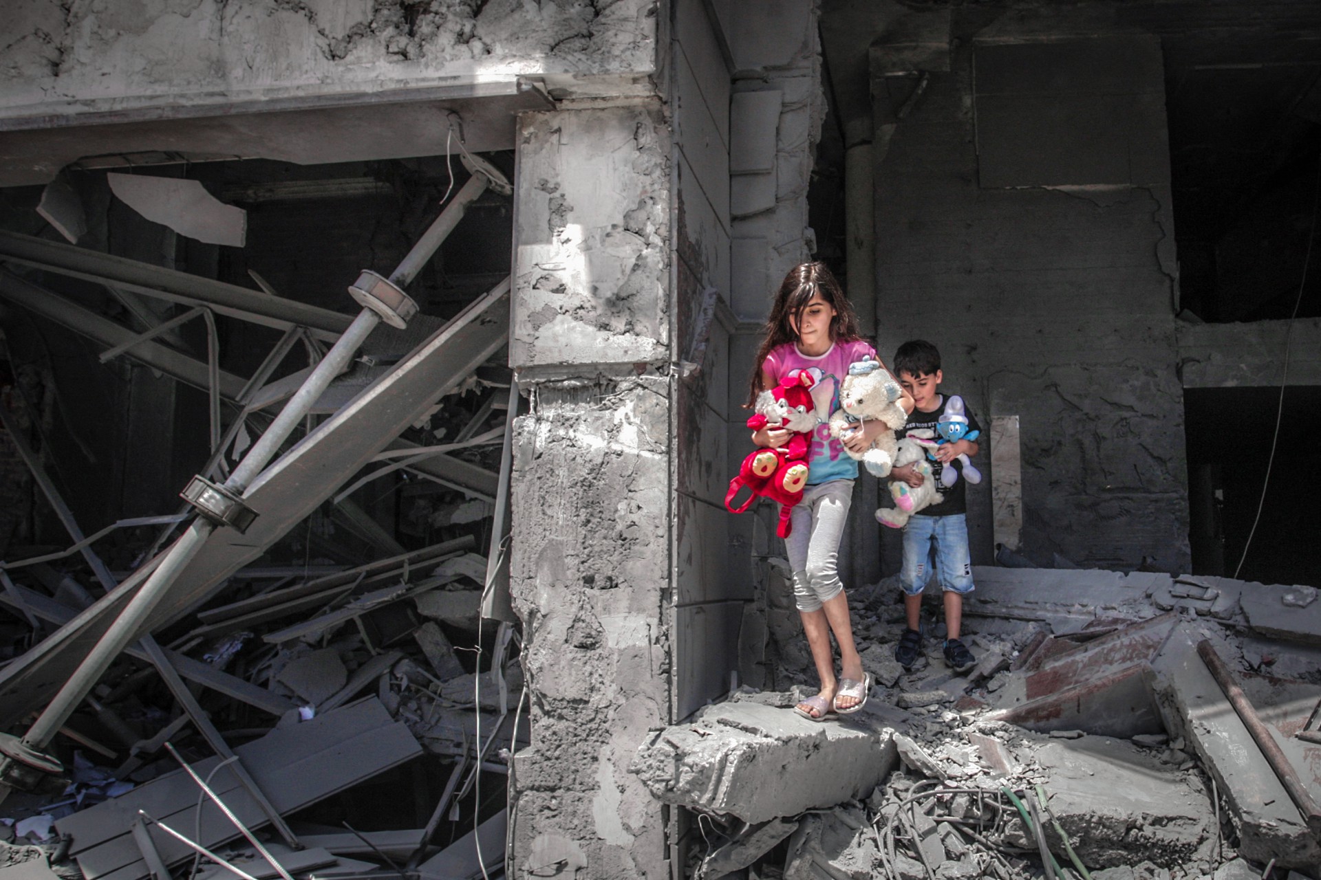 Crianças palestinas resgatam brinquedos de sua casa na Torre Al-Jawhara na Cidade de Gaza, em 17 de maio de 2021, que foi fortemente danificada em ataques aéreos israelenses. (Foto: ANAS BABA / AFP)