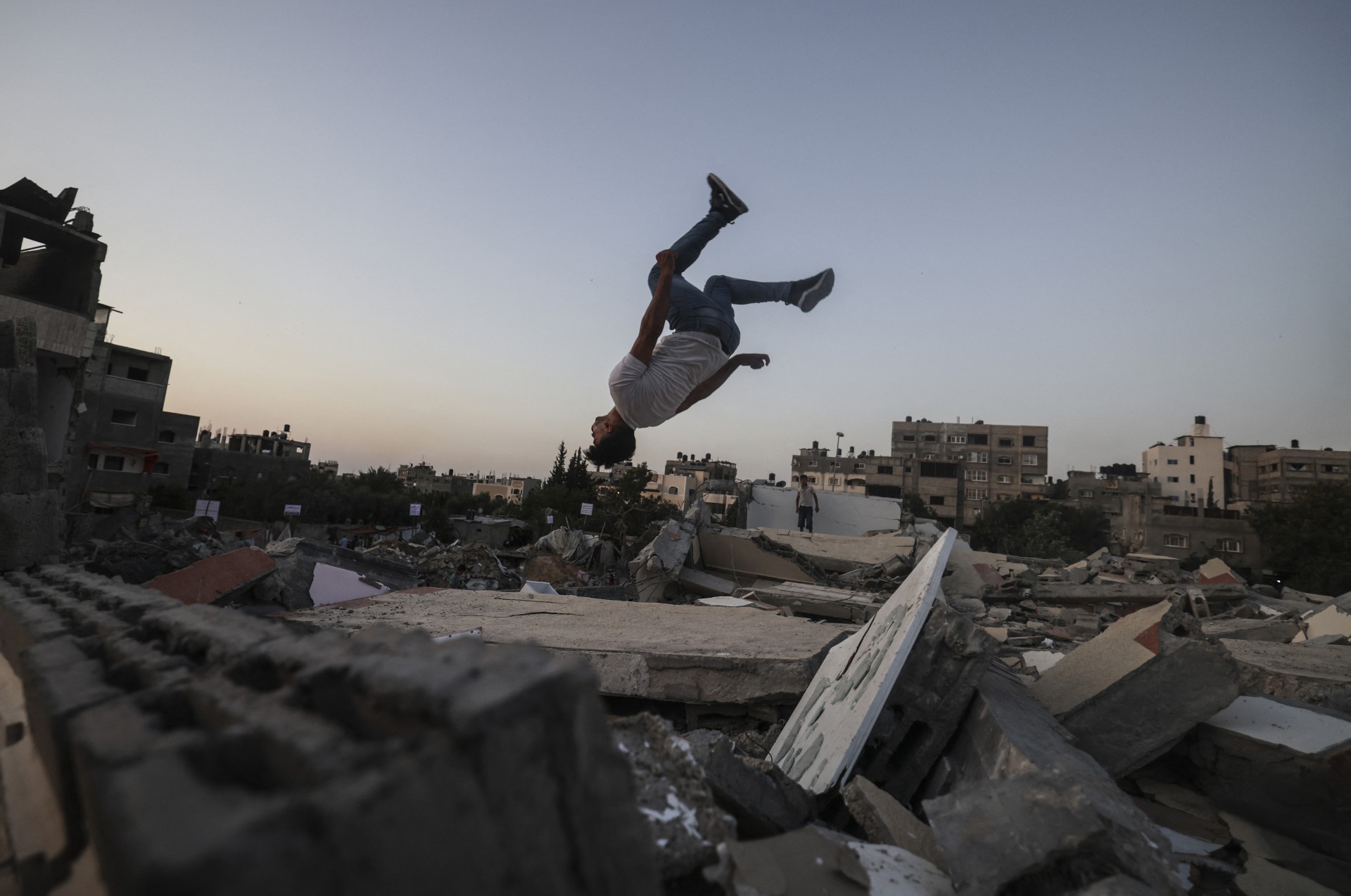 Palestinian youths play parkour on top of the ruins of a building destroyed in recent Israeli air strikes, in Beit Lahia in the northern Gaza Strip, on May 25, 2021. - A ceasefire was reached late last week after 11 days of deadly violence between Israel and the Hamas movement which runs Gaza, stopping Israel's devastating bombardment on the overcrowded Palestinian coastal enclave which, according to the Gaza health ministry, killed 248 Palestinians, including 66 children, and wounded more than 1,900 people. Meanwhile, rockets from Gaza claimed 12 lives in Israel, including one child and an Israeli soldier. (Photo by MAHMUD HAMS / AFP) (Foto: AFP)