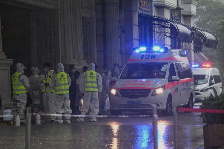 Profissionais de saúde usando equipamento de proteção individual (EPI) estão na entrada do Legendale Hotel, no distrito comercial de Wangfujing, em Pequim, em 29 de julho de 2021, depois que a China relatou surtos de vírus em três cidades