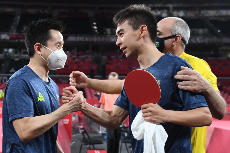 O brasileiro Vitor Ishiy (R) comemora com o brasileiro Gustavo Tsuboi (L) após vencer sua partida durante a partida de tênis de mesa da equipe masculina das oitavas de final no Ginásio Metropolitano de Tóquio durante os Jogos Olímpicos de Tóquio 2020 em Tóquio em 1º de agosto de 2021