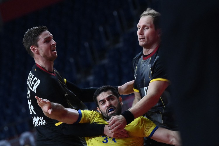 O lateral-esquerdo brasileiro Leonardo Dutra Ferreira (C) é desafiado pelo pivô alemão Hendrik Pekeler (L) e pelo lateral direito alemão Steffen Weinhold durante a rodada preliminar masculina do grupo Uma partida de handebol entre Alemanha e Brasil dos Jogos Olímpicos de Tóquio 2020 no Estádio Nacional de Yoyogi em Tóquio em 1º de agosto de 2021.