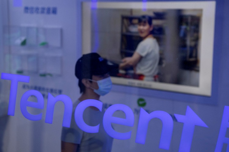 Esta foto de arquivo tirada em 6 de setembro de 2020 mostra uma mulher passando por uma placa da Tencent na Feira Internacional de Comércio de Serviços da China (CIFTIS) em Pequim.