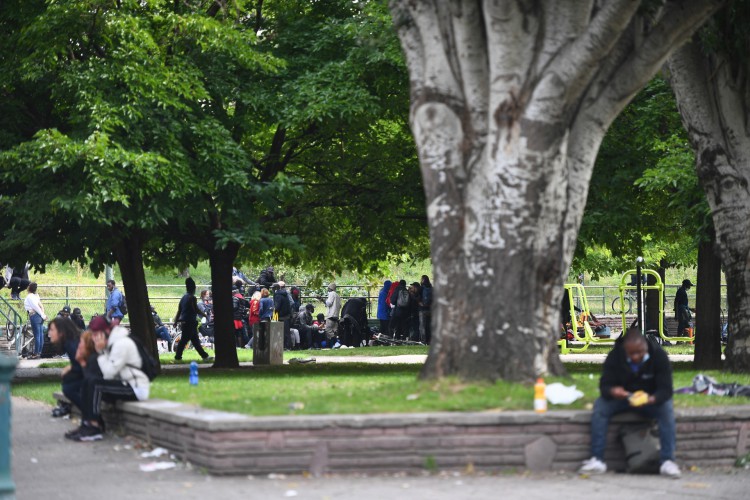 Pessoas sentam-se depois de serem realocadas perto da Porte de la Villette, norte de Paris, em 24 de setembro de 2021, após uma operação policial para expulsar usuários de crack no distrito de jardins Eole