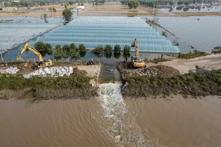 Foto aérea tirada em 11 de outubro de 2021 mostra equipes de resgate cavando um vertedouro com uma escavadeira para liberar as águas da enchente após fortes chuvas em uma área inundada em Jiexiu, nesta terça, 12