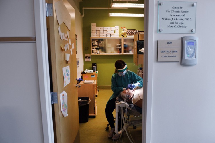 Chaina Cooper, uma higienista dental registrada, trabalha com a paciente Maria A. Hernandez, 53, na clínica odontológica em Bread for the City