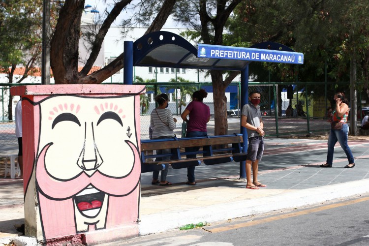 Pessoas em parada de ônibus aguardando coletivo. Prefeito de Maracanaú assinou projeto de lei do passe livre para estudantes e pessoas inscritas no cadastro único