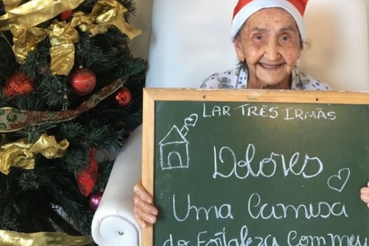 Dona Dolores segurando o quadro de giz com o pedido pela camisa do Fortaleza de natal