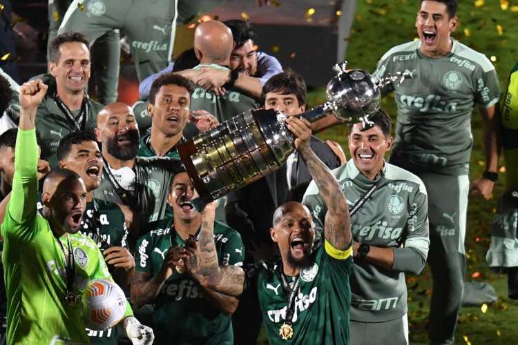 Palmeiras' Felipe Melo (C) celebrates with teammates with the trophy of the Copa Libertadores football tournament after defeating Flamengo in the all-Brazilian final match, at the Centenario stadium in Montevideo, on November 27, 2021. (Photo by EITAN ABRAMOVICH / AFP).