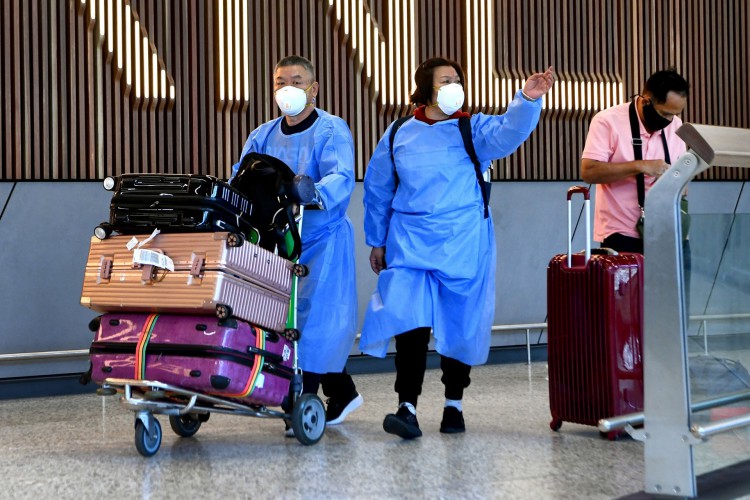 Os viajantes internacionais usando equipamento de proteção individual (PPE) chegam ao Aeroporto Tullamarine de Melbourne, na Australia, em 29 de novembro de 2021