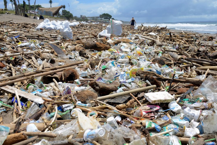 Turistas estrangeiros ajudam a coletar sacos de lixo depois de destroços na praia de Batu Belig, na regência de Badung, depois que ela foi destruída após uma tempestade na ilha balneária de Bali, na Indonésia, em 14 de dezembro de 2021