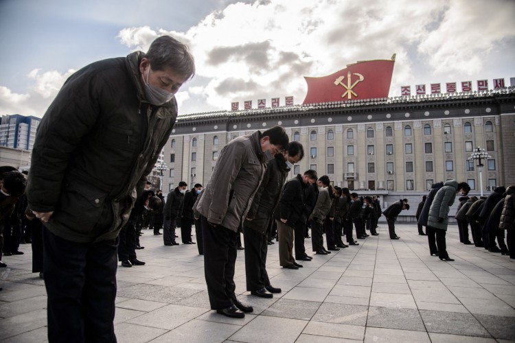 As pessoas se curvam durante um silêncio de três minutos para prestar seus respeitos aos retratos de Kim Il Sung e Kim Jong Il, para marcar o 10º aniversário da morte de Kim Jong Il, o pai do atual líder Kim Jong Un, na Praça Kim Il Sung em Pyongyang em 17 de dezembro de 2021