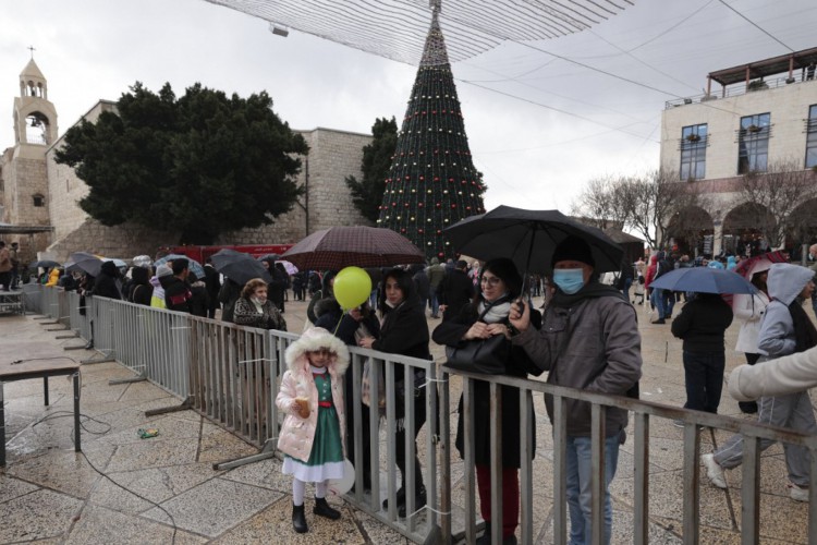 As pessoas se reúnem do lado de fora da Igreja da Natividade, venerada como o local do nascimento de Jesus Cristo, durante as celebrações do Natal na cidade bíblica de Belém, na Cisjordânia ocupada por israelenses, em 24 de dezembro de 2021.
Foto: ABBAS MOMANI / AFP
