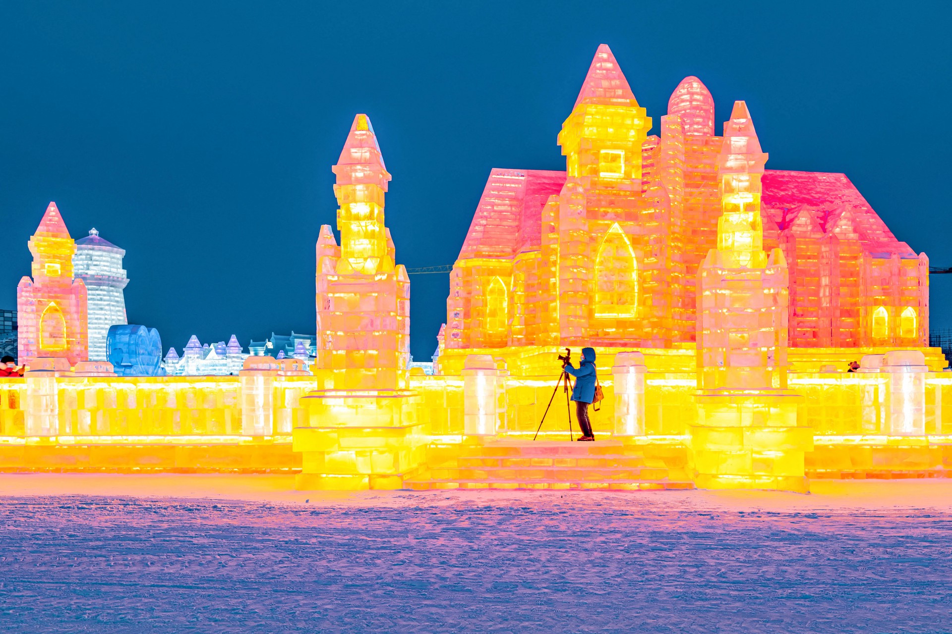 Esta foto tirada em 28 de dezembro de 2021 mostra um homem tirando fotos de esculturas de gelo no Harbin Ice and Snow World em Harbin, na província de Heilongjiang no nordeste da China.
 (Foto: STR / AFP )