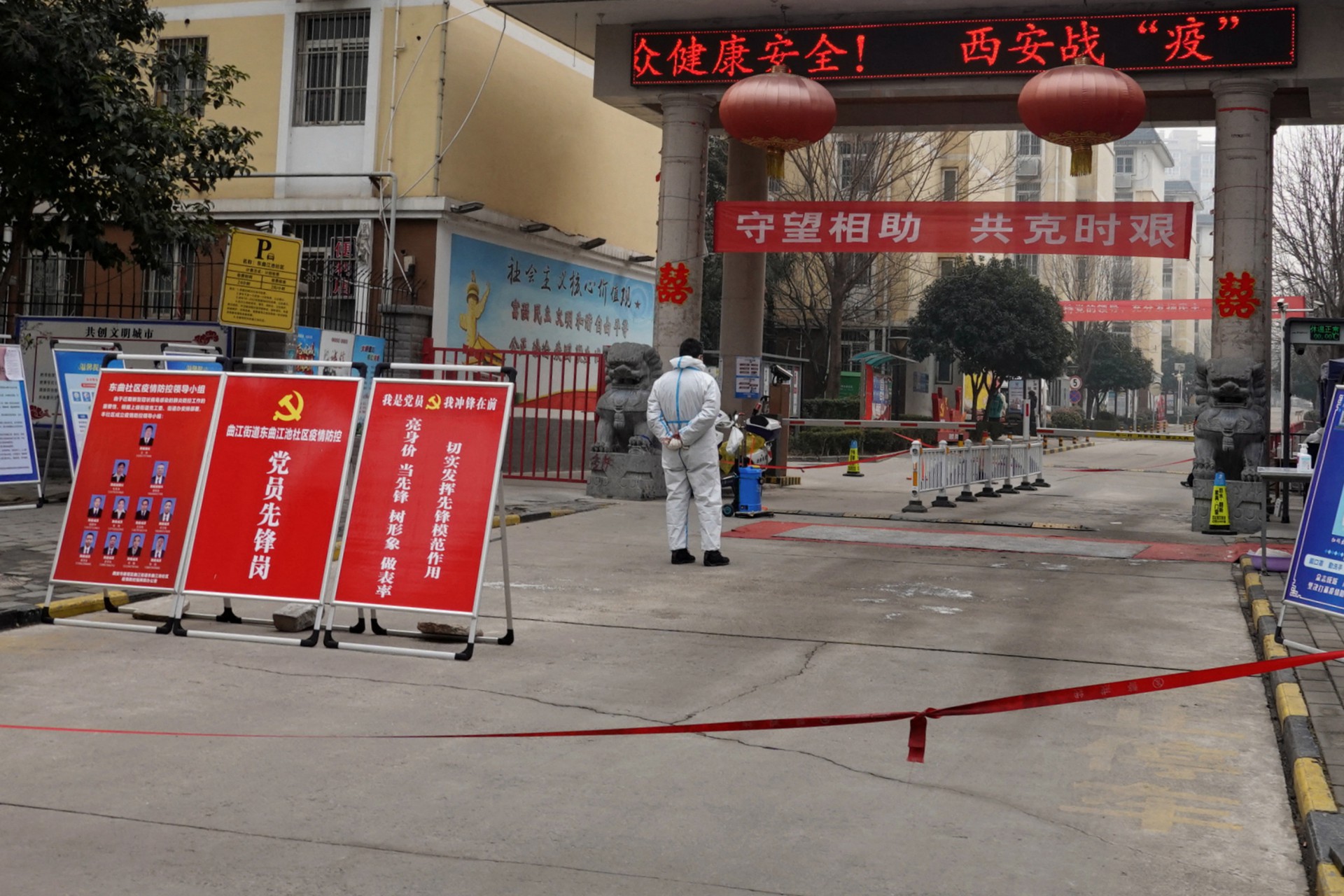 Homem com traje de proteção monta guarda na entrada de um complexo residencial em Xi'an, na província de Shaanxi, no norte da China (Foto: STR / AFP)