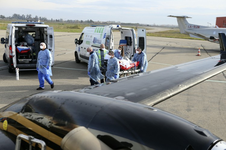 Paramédicos, enfermeiras e médicos usam um bonde para transferir um paciente afetado por coronavírus (Covid-19) de uma ambulância para uma aeronave médica em Bastia, na ilha mediterrânea francesa da Córsega em 5 de janeiro de 2022, antes de voar para a cidade de Brest, França ocidental