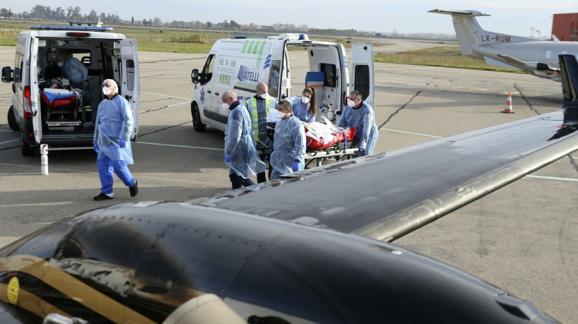 Paramédicos, enfermeiras e médicos usam um bonde para transferir um paciente afetado por coronavírus (Covid-19) de uma ambulância para uma aeronave médica em Bastia, na ilha mediterrânea francesa da Córsega em 5 de janeiro de 2022, antes de voar para a cidade de Brest, França ocidental(foto: PASCAL POCHARD-CASABIANCA / AFP)