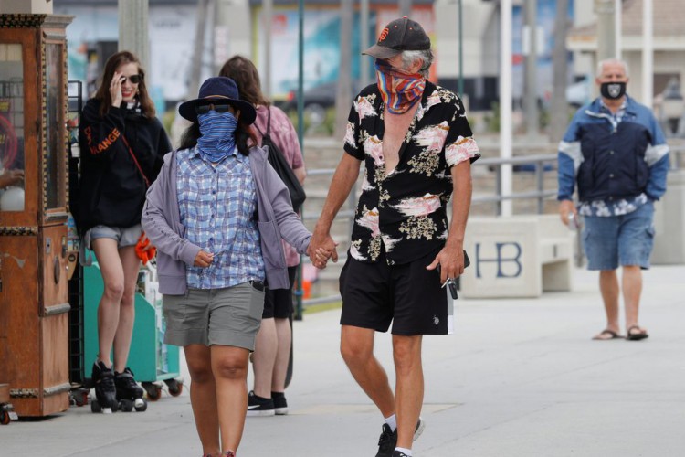 Pessoas que usam máscaras caminham ao longo do cais do oceano enquanto os Estados Unidos passaram na quinta-feira um total de mais de 4 milhões de infecções por coronavírus durante o surto global da doença por coronavírus (COVID-19) em Huntington Beach, Califórnia, EUA, em 23 de julho de 2020 REUTERS / Mike Blake