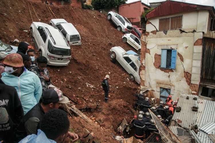 Bombeiros vasculham escombros depois que um estacionamento que abrigava vários carros particulares desabou em casas após as fortes chuvas dos últimos dias no bairro Ankadifotsy de Antananarivo em 24 de janeiro de 2022