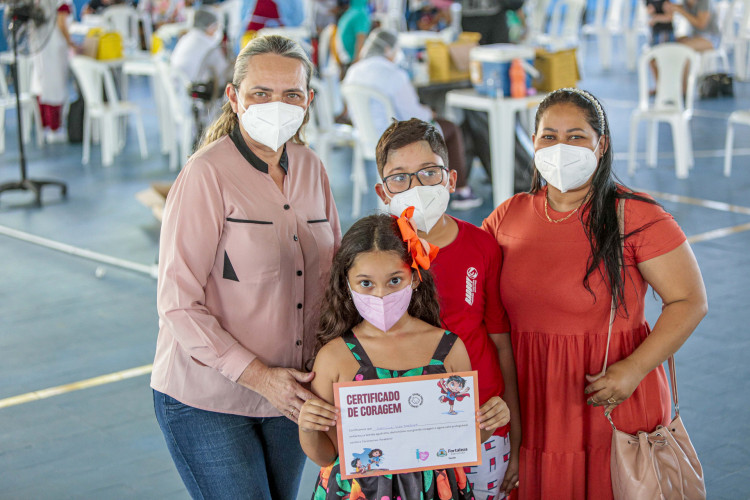 A pequena e corajosa Carolina Lira Barbosa, 7, vacinou-se contra a Covid-19 neste domingo, 6. Estava acompanhada da avó, Isabel Cristina Falcão, 52; do irmão, Matheus Lira Barbosa, 11, e da mãe, Maria Claudiana de Oliveira Lima, 40