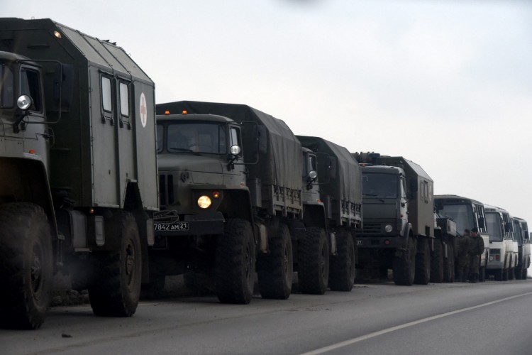 Caminhões e ônibus militares russos são vistos ao lado de uma estrada na região sul de Rostov, na Rússia, que faz fronteira com a autoproclamada República Popular de Donetsk, em 23 de fevereiro de 2022.
