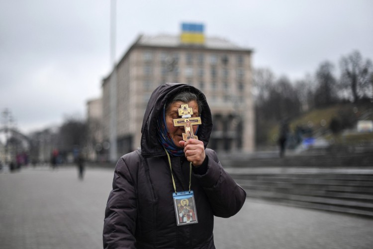 Uma religiosa segura uma cruz enquanto reza na Praça da Independência em Kiev, na manhã de 24 de fevereiro de 2022.