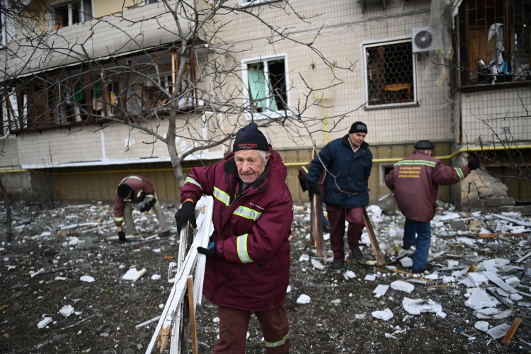 Homens limpam destroços em um prédio residencial danificado na rua Koshytsa, um subúrbio da capital ucraniana Kiev