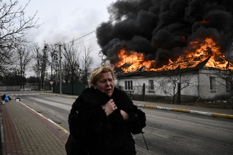 Uma mulher reage em frente a uma casa em chamas após ser bombardeada na cidade de Irpin, nos arredores de Kiev, em 4 de março de 2022. - Mais de 1,2 milhão de pessoas fugiram da Ucrânia para países vizinhos desde que a Rússia lançou sua invasão em grande escala em 24 de fevereiro, os números das Nações Unidas mostraram em 4 de março de 2022