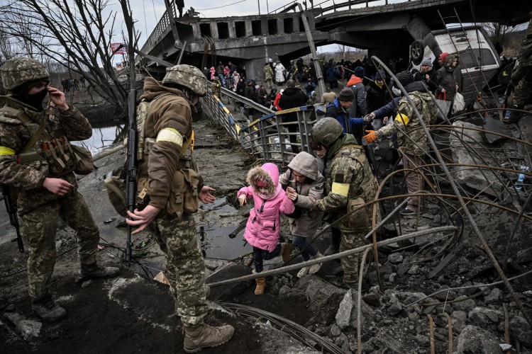 Pessoas atravessam uma ponte destruída ao evacuar a cidade de Irpin, a noroeste de Kiev, durante bombardeios pesados da Rússia