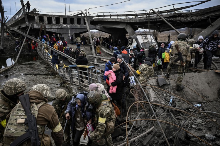 Pessoas atravessam uma ponte destruída ao evacuar a cidade de Irpin, a noroeste de Kiev, durante bombardeios