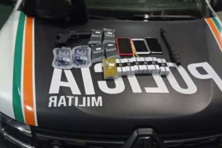 Material apreendido com o jovem durante abordagem policial. Na foto, celulares, caixas de preservativo, de medicamentos e um simulacro de arma de fogo são vistos em cima de uma viatura da Polícia Militar