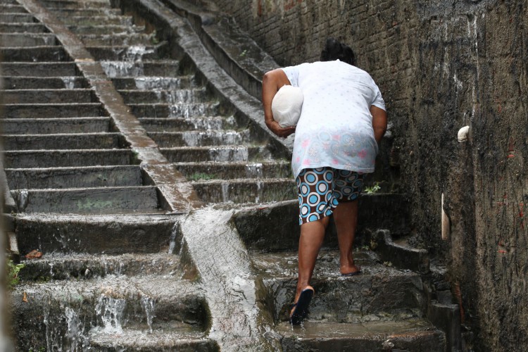 Há 40 dias, chove em Fortaleza cotidianamente. Na foto, moradores do bairro Vicente Pinzón tentam subir escada de acesso molhada pela chuva