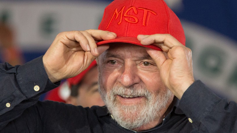 (FILES) In this file photo taken on March 19, 2022, former Brazilian President Luiz Inacio Lula da Silva adjusts his cap during a meeting with members of the Landless Workers Movement (MST), at the Eli Vive camp in Londrina, Parana State, Brazil. - Leftist ex-president Luiz Inacio Lula da Silva is scheduled to launch his campaign for Brazil's October elections on May 7, 2022, seeking to unseat far-right President Jair Bolsonaro and stage a remarkable comeback four years after being jailed for corruption. More than a decade after leaving office as the most popular president in Brazilian history, the charismatic but tarnished 76-year-old is expected to officially declare a new run at a huge rally in Sao Paulo. (Photo by Ricardo CHICARELLI / AFP)