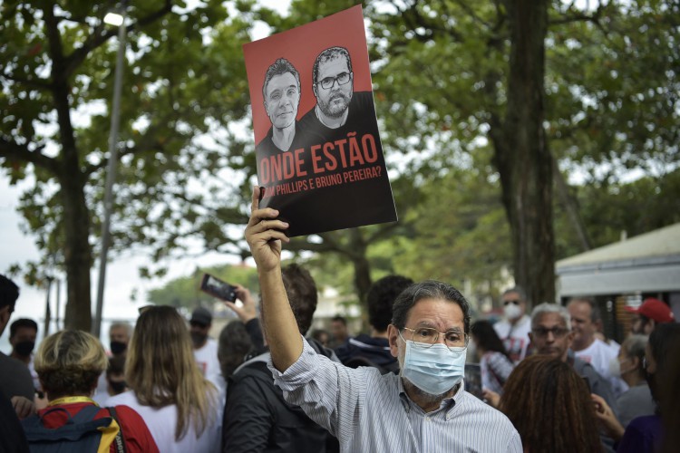 ￼Manifestante segura cartaz com fotos de jornalista e indigenista