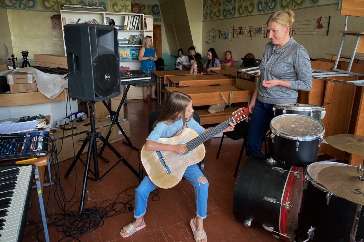 A professora Tetyana Kryvosheyenko acompanha uma de suas alunas na aula de violão