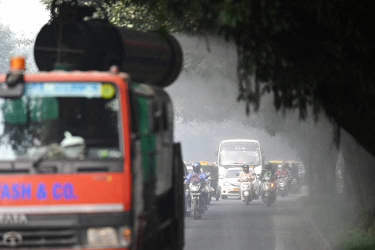 Passageiros passam por uma arma anti-smog que pulveriza água para conter a poluição do ar em meio a fortes condições de smog em Nova Délhi, em 4 de novembro de 2022