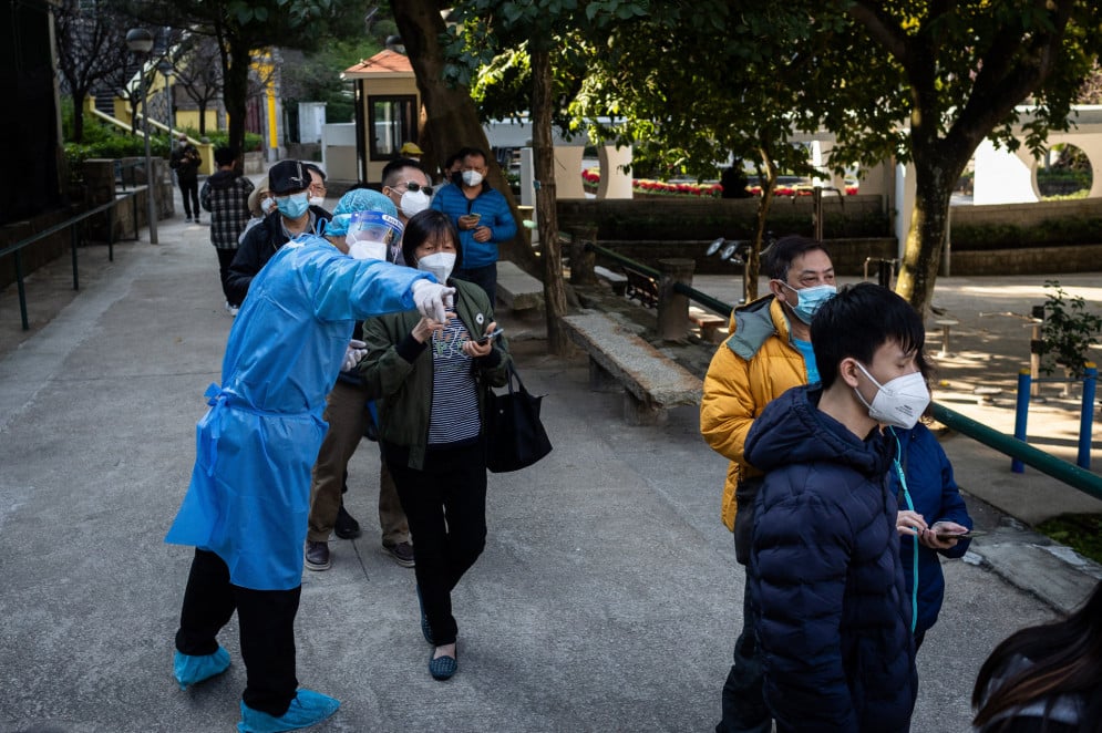 Com o celular em mãos, chineses aguardam para teste de Covid em Macau, em 21 de dezembro de 2022(Foto: EDUARDO LEAL / AFP)