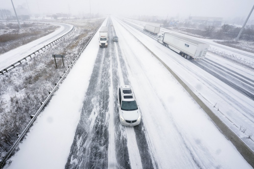 O tráfego flui lentamente ao longo de uma rodovia 401 coberta de neve em Ontário, Canadá, durante uma grande tempestade de inverno(Foto: GEOFF ROBINS / AFP)