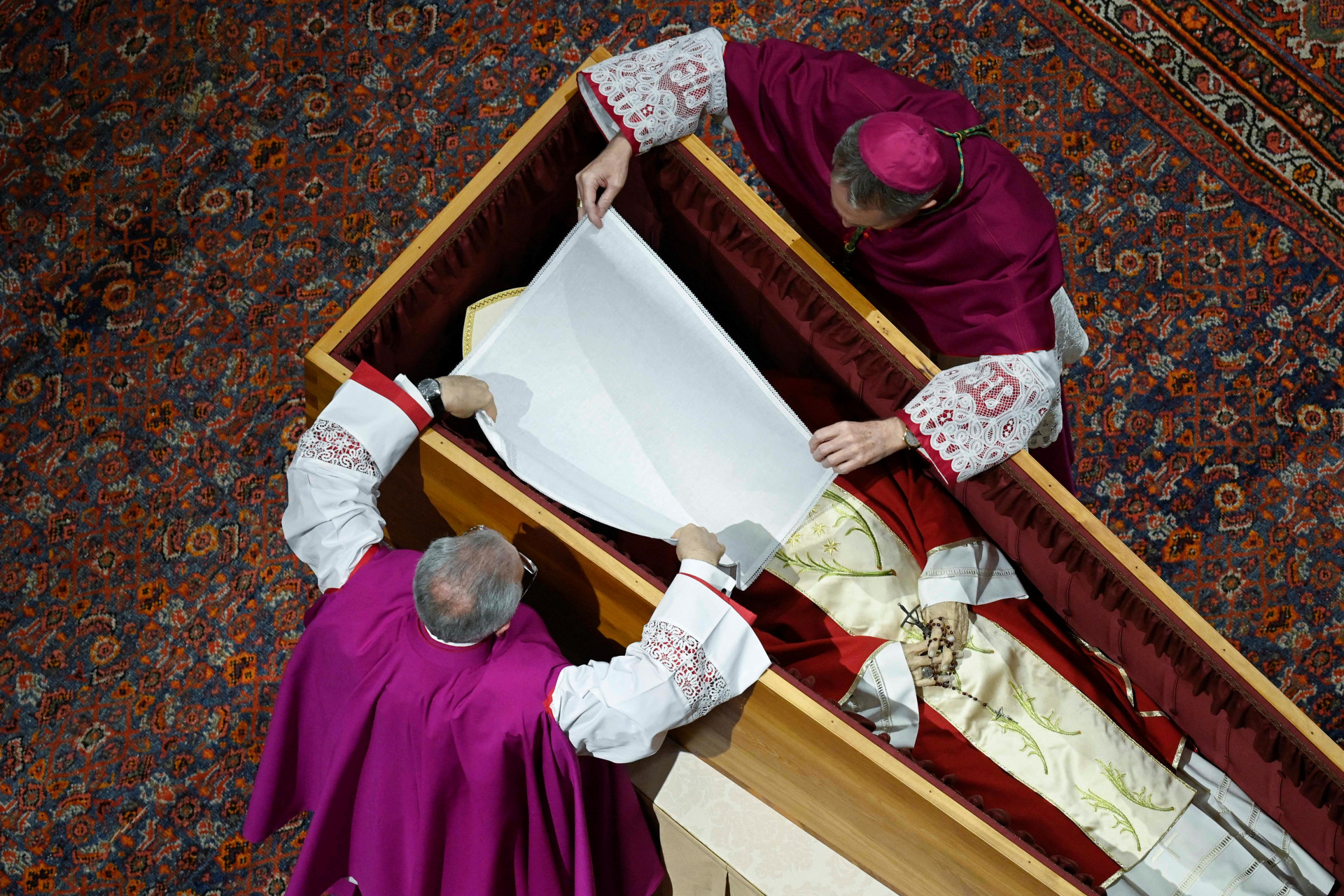 Esta fotografia de folheto tirada e divulgada pela Mídia do Vaticano em 5 de janeiro de 2023 mostra funcionários preparando o caixão do falecido Papa Emérito Bento XVI na Basílica de São Pedro no Vaticano. O Papa Francisco conduziu o funeral de seu predecessor Bento XVI na frente de dezenas de milhares de enlutados na Praça de São Pedro, um evento sem precedentes nos tempos modernos. Cardeais vestidos de escarlate, dignitários e milhares de padres e freiras de todo o mundo se reuniram para se despedir do teólogo alemão, que surpreendeu a Igreja Católica em 2013 ao se tornar o primeiro pontífice em seis séculos a renunciar.
 (Foto: VATICANO MEDIA / AFP)