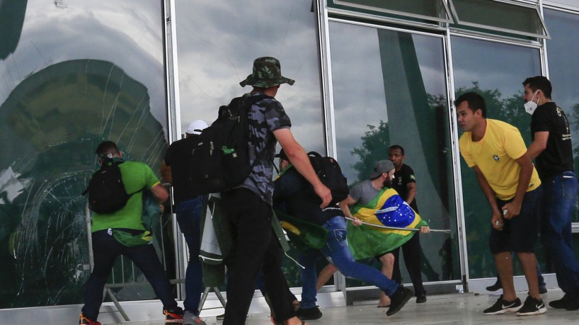 Supporters of Brazilian former President Jair Bolsonaro break a window as they invade Planalto Presidential Palace in Brasilia on January 8, 2023. - Hundreds of supporters of Brazil's far-right ex-president Jair Bolsonaro broke through police barricades and stormed into Congress, the presidential palace and the Supreme Court Sunday, in a dramatic protest against President Luiz Inacio Lula da Silva's inauguration last week. (Photo by Sergio Lima / AFP)